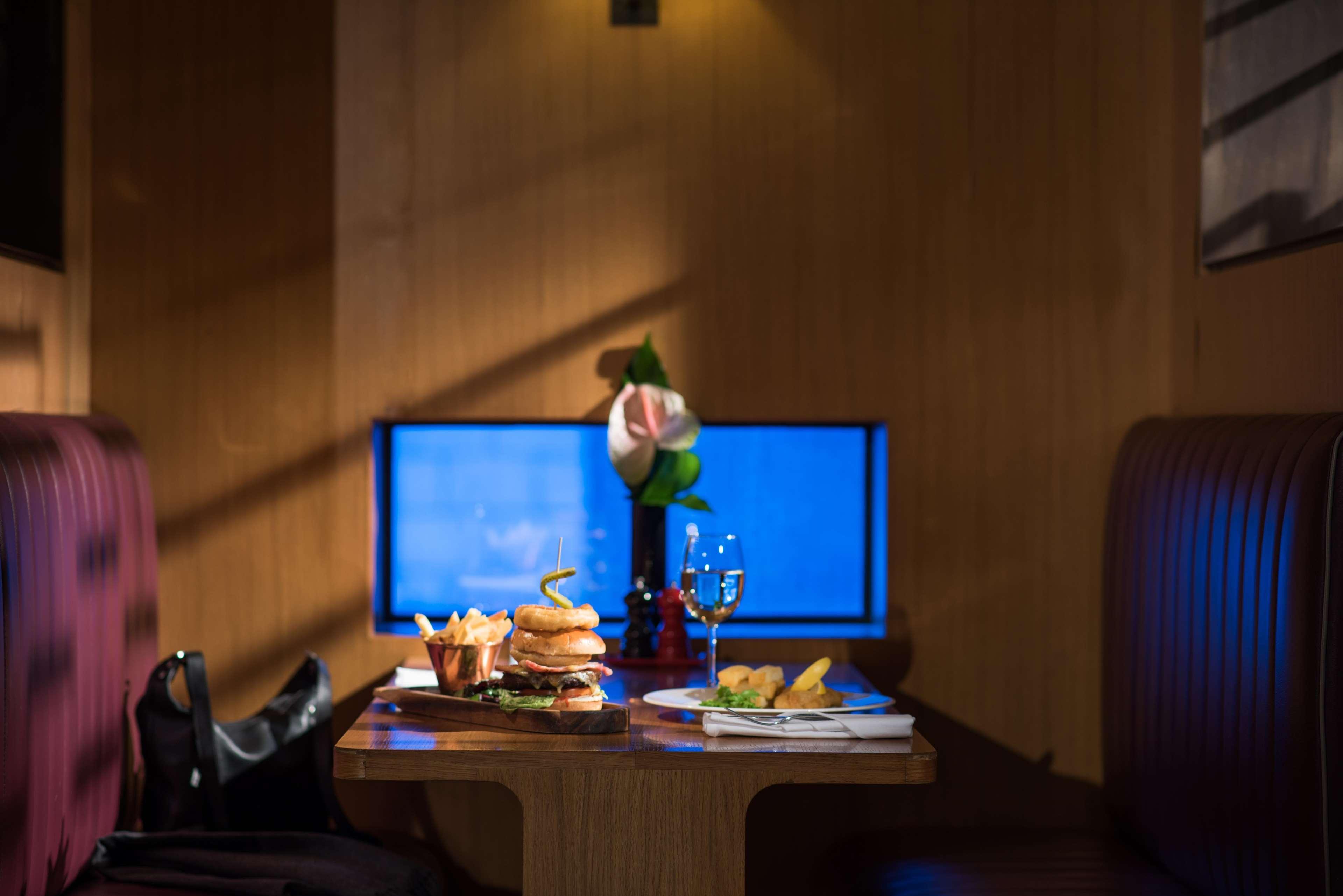 The Fitzwilliam Hotel Белфаст Екстериор снимка The photo shows a dining table set in a cozy restaurant environment. On the table, there are several food items, including a large burger, some fries, and a small plate with additional items. A glass of wine or another beverage is also present. In th